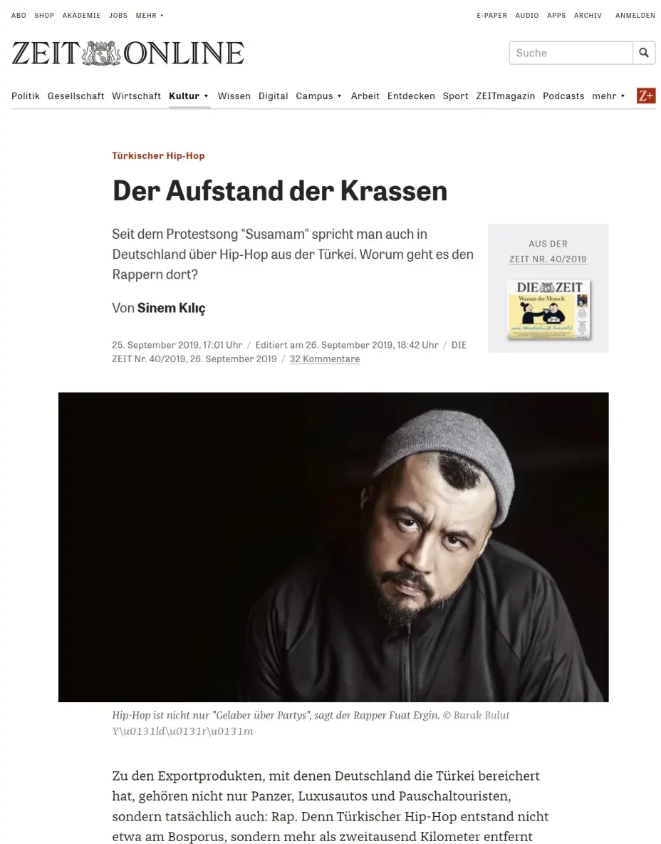 Filmisches Musikerporträt eines bärtigen Rappers mit grauer Mütze, strenger Blick, zurückhaltende Studiobeleuchtung.