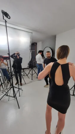 Photo of a musician preparing for a shoot in a studio, featuring lighting equipment and photographers capturing the moment.