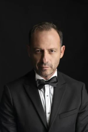 Cinematic studio portrait of a serious man in a black tuxedo and bow tie, a confident professional headshot.