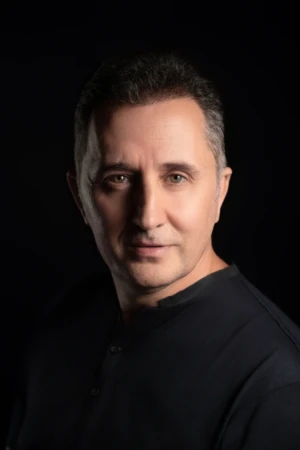 Studio professional headshot of a middle-aged man with a confident expression, dark shirt and cinematic studio lighting.