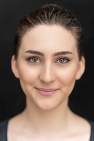 Close-up acting headshot of a woman smiling gently against a black background with soft, authentic studio light in Berlin.