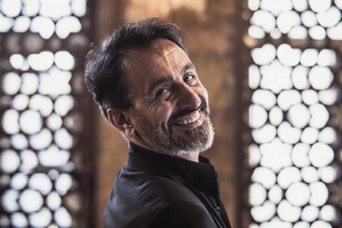 Smiling bearded man in warm natural light with decorative backlit window, an authentic professional headshot.