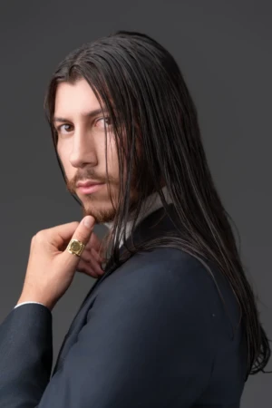 Moody studio portrait of a long-haired man in a suit with a thoughtful expression, cinematic actor headshot.