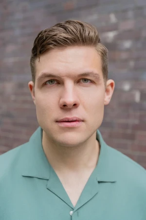 Man in green shirt, brick background.
