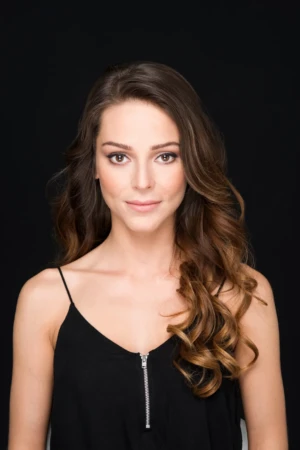 Confident woman wearing a black top against a black background, lit with soft studio light, professional headshot.