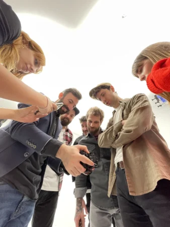 Photographer and a group huddle over a camera in a bright studio for an authentic behind-the-scenes team portrait review.